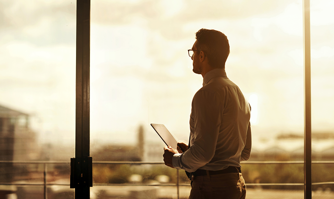A professional looking out of an office window.