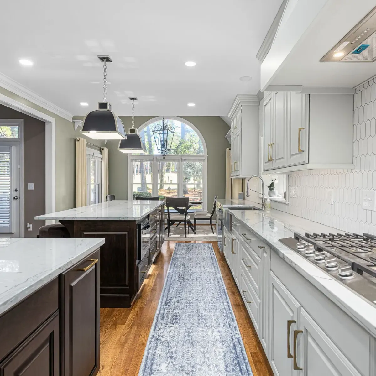 High-end kitchen renovation in the Badin Lake, North Carolina area with custom white cabinets, stone countertops, stainless steel appliances, and a spacious center island. Designed and built by an experienced kitchen remodeling contractor.
