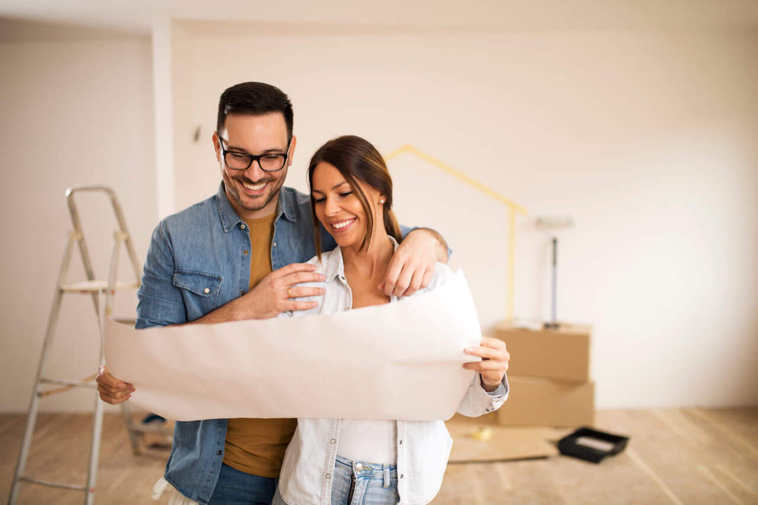 Homeowners reviewing a large plan during a home improvement project. The image represents the planni 