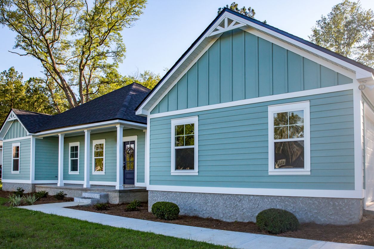 A charming blue home features horizontal and vertical siding, bright white trim, decorative gable ac 