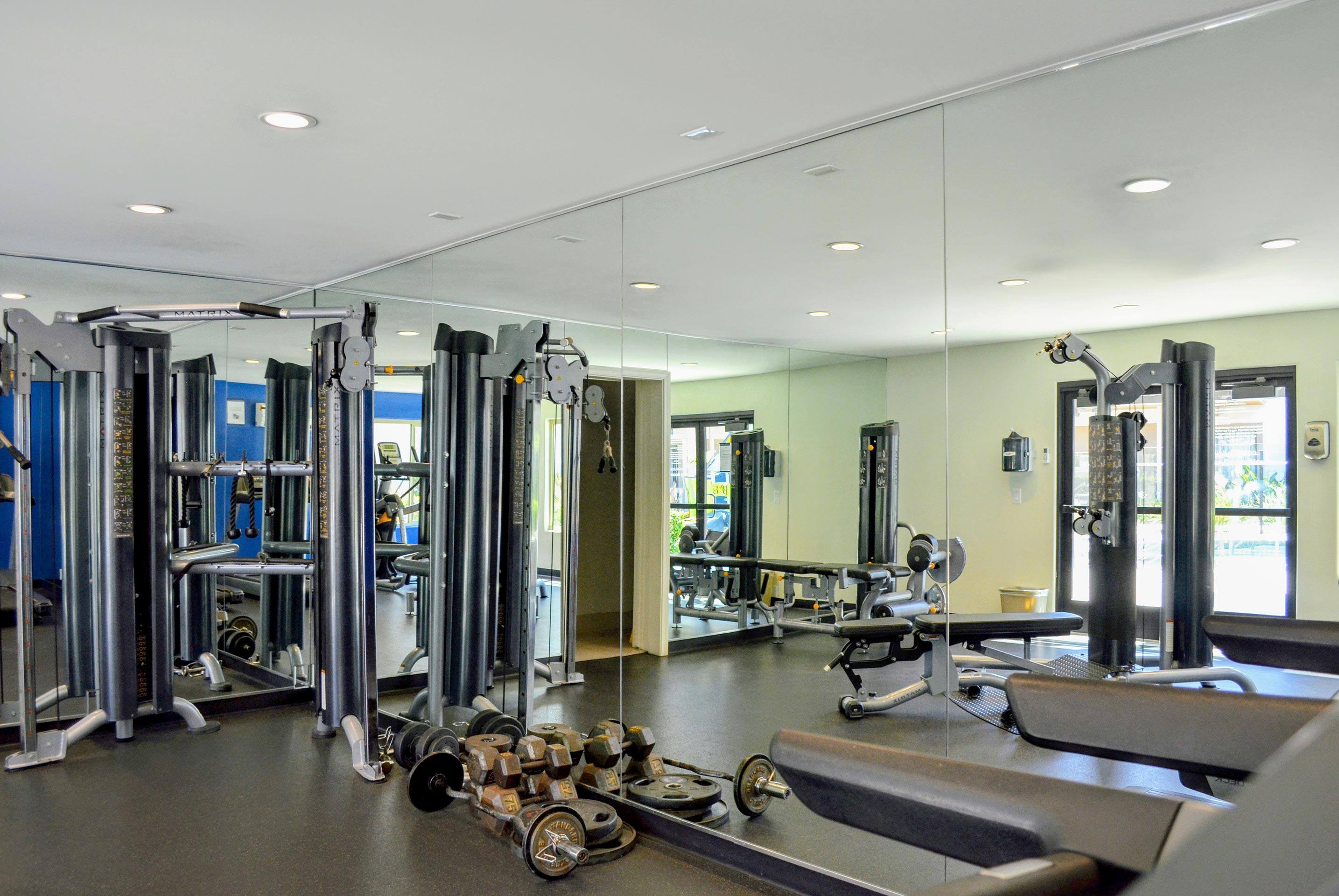 A gym with a variety of equipment including treadmills, weights, and exercise machines.