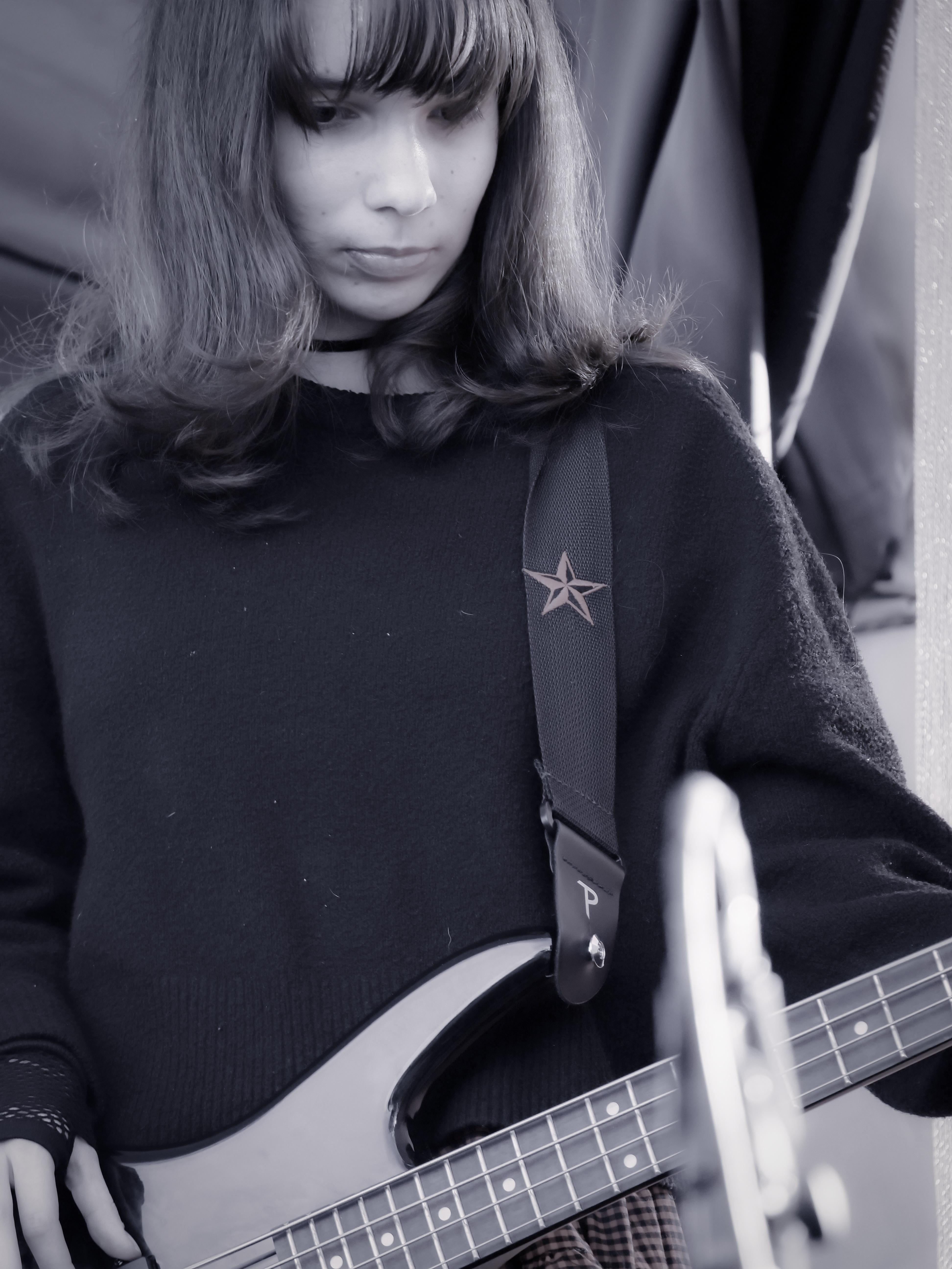 Black-and-white photo of a student bassist performing live during a music performance program.