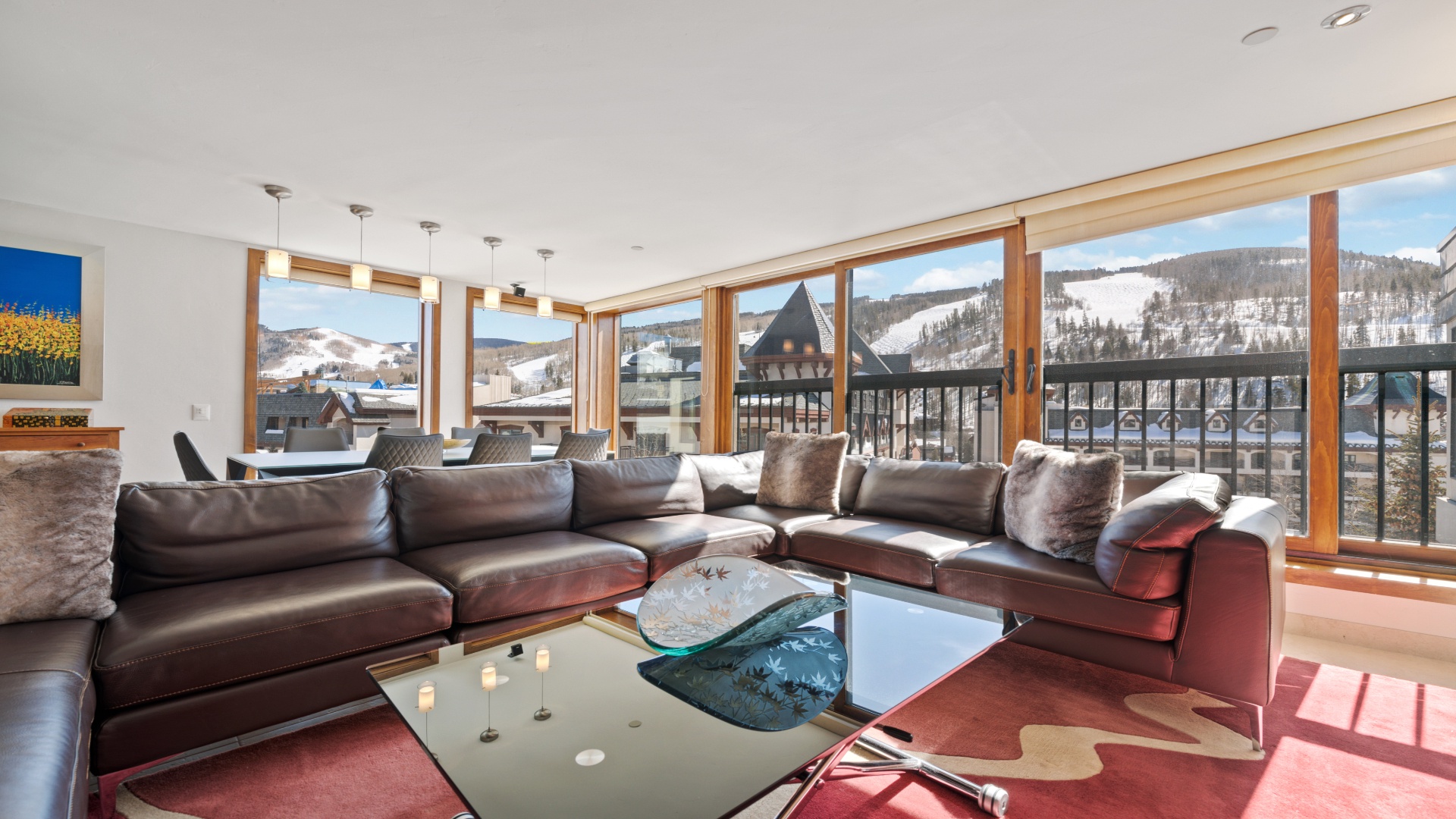The luxurious living room with a large couch and windows looking out to the snow-covered town and mo 