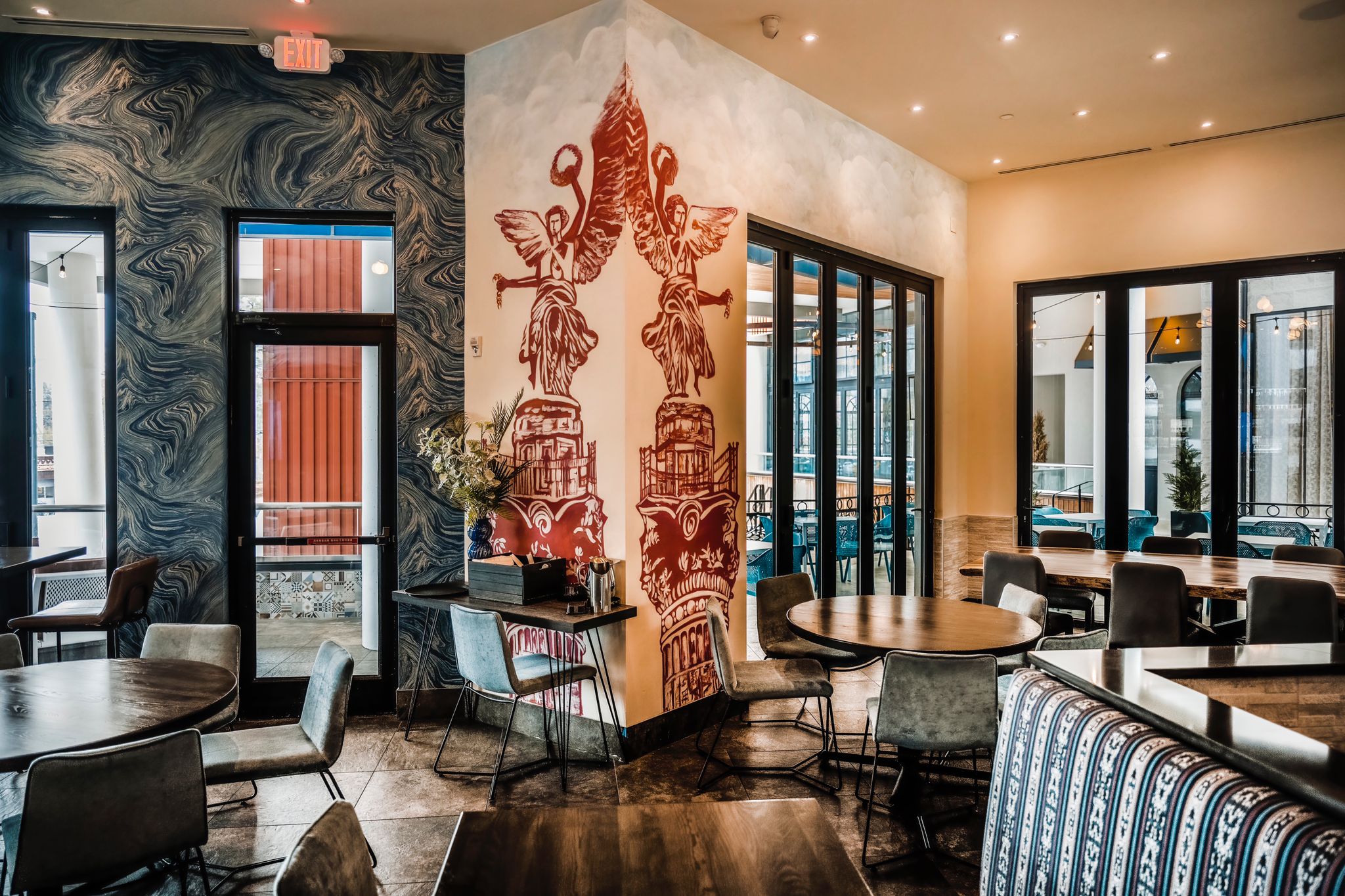 The blue accents on the wall create a calming effect, contrasting beautifully with the warm tones of the mural art. The corner feels intentional, adding a touch of sophistication to the dining experience.