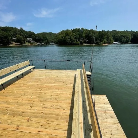 Wooden dock with built-in bench overlooking calm lake and trees.