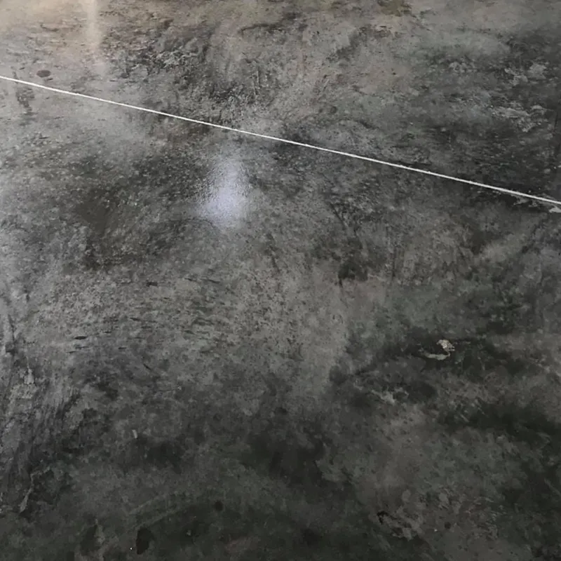 A close-up, top-down view of a dark, mottled concrete floor with a thin white string or wire stretched across it diagonally.