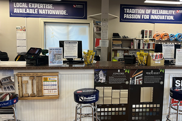 Contractor service desk at Builders FirstSource New Bedford featuring product samples, brochures, and signage promoting nationwide expertise and reliable service.