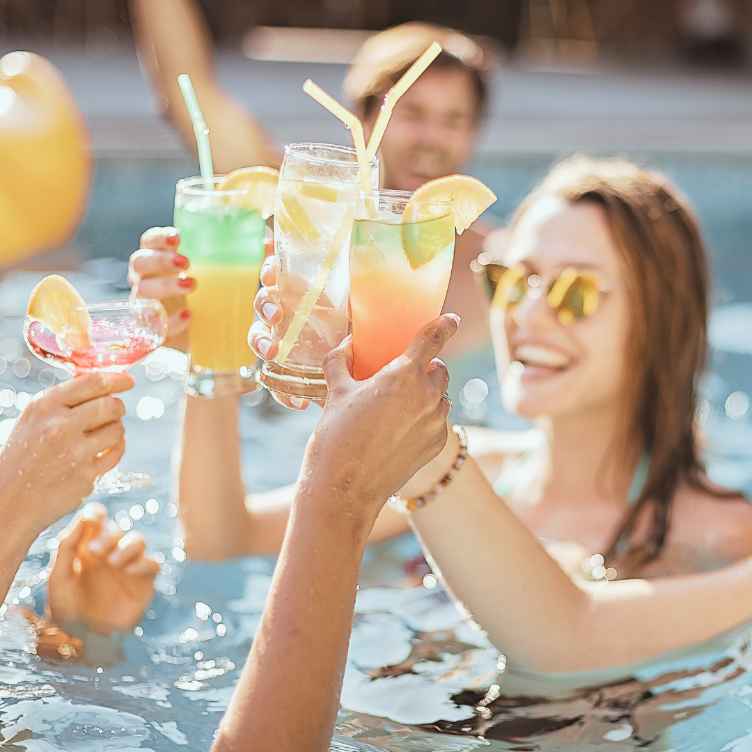 Friends celebrating poolside with refreshing drinks on a sunny day