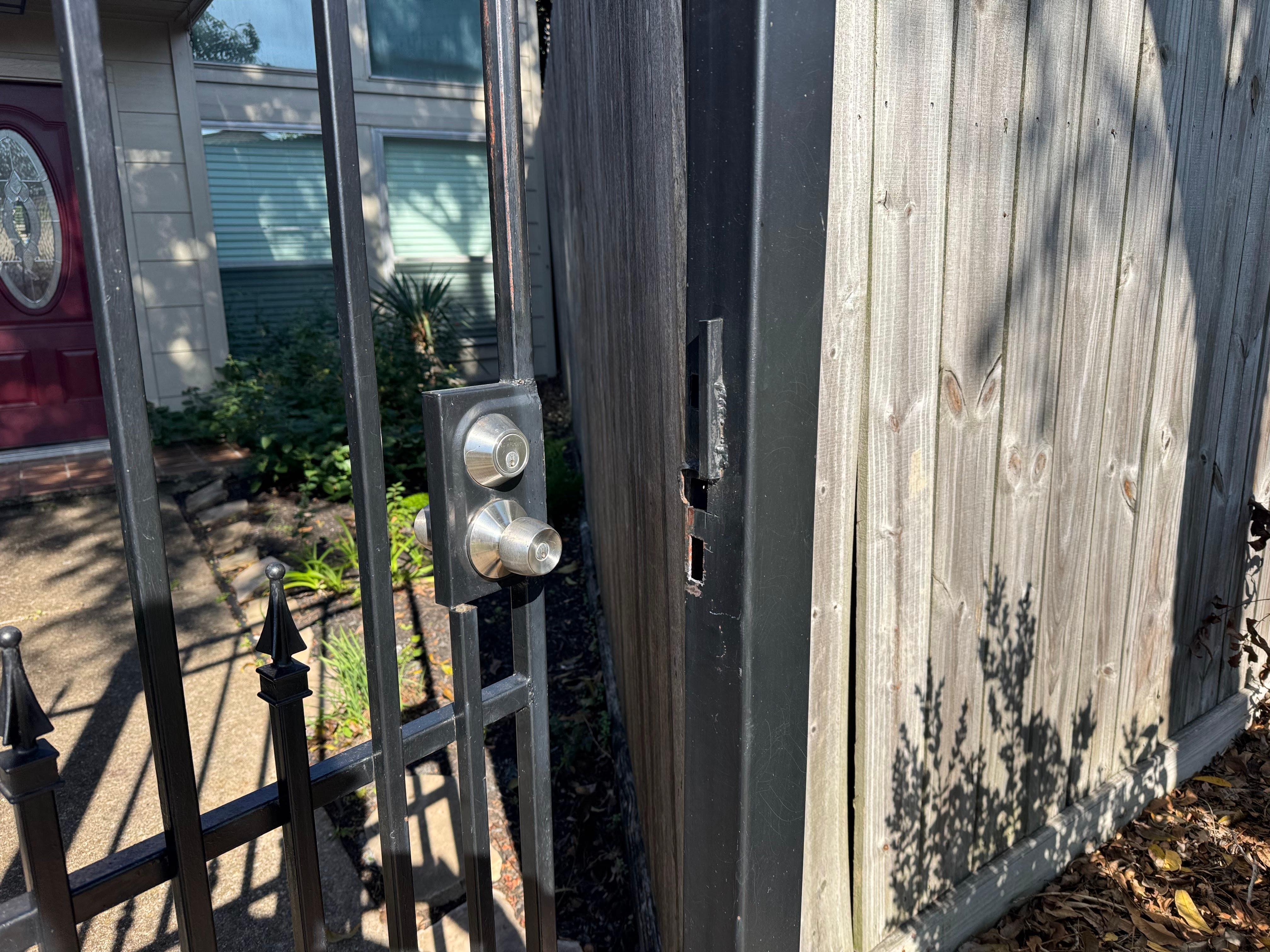 Residential black wrought iron gate with repaired latch and lock mechanism.