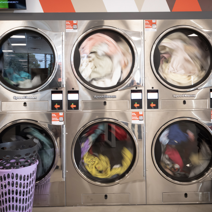 High-capacity commercial dryers filled with laundry at a Speed Queen Laundry self-service laundromat 