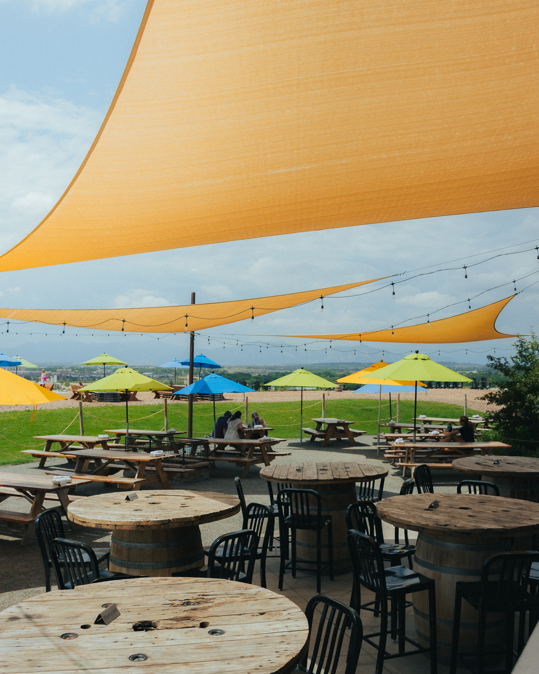 Guests relax on the Acreage patio while enjoying hard cider, seasonal food, and panoramic views of the Rocky Mountains.