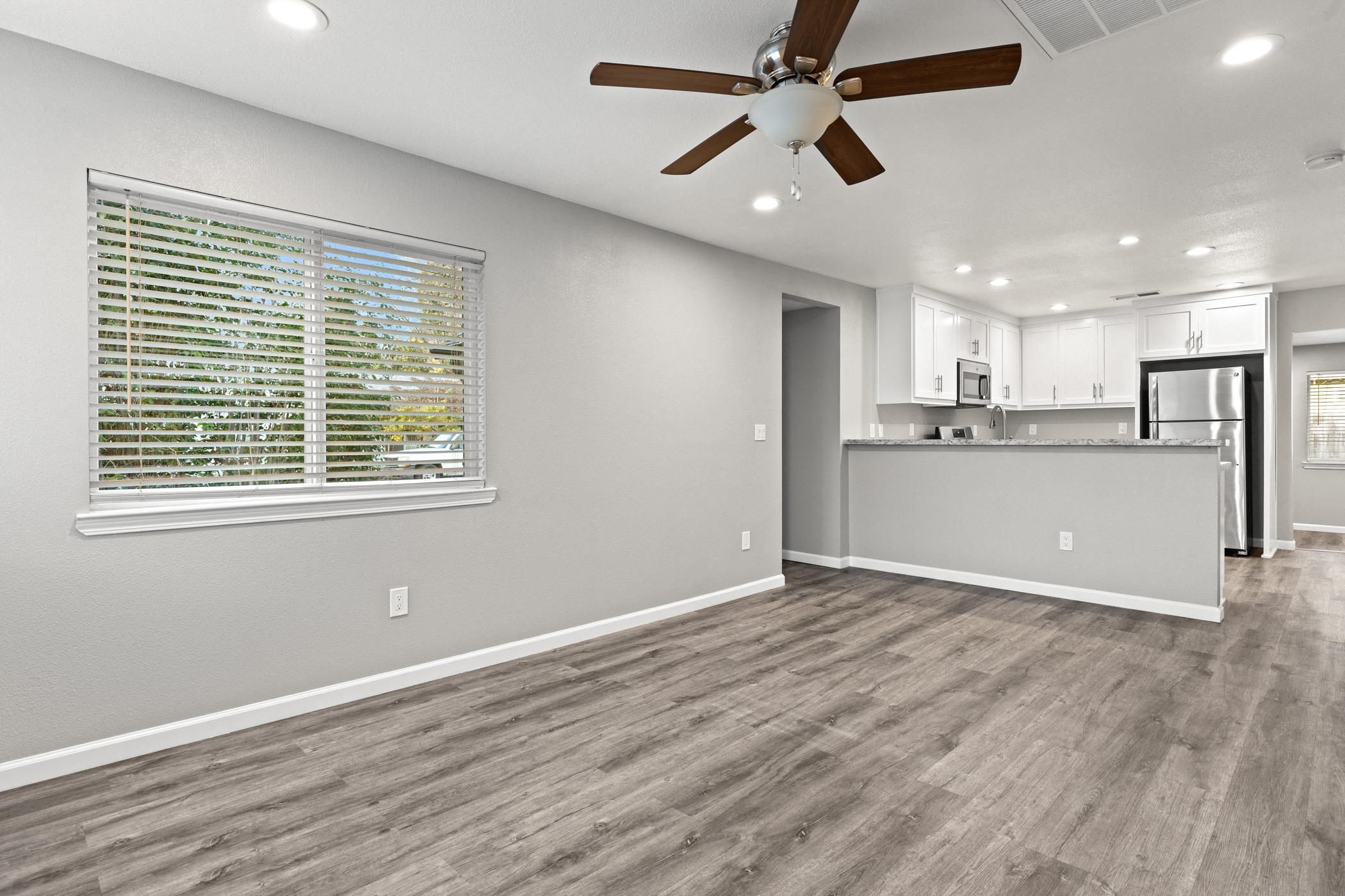 A room with a ceiling fan and a window with blinds.