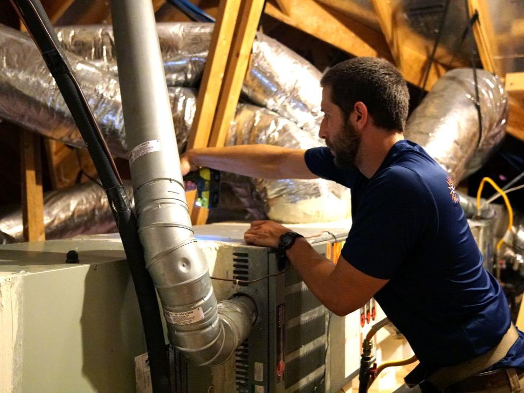 HVAC tech working on a furnace in an attic