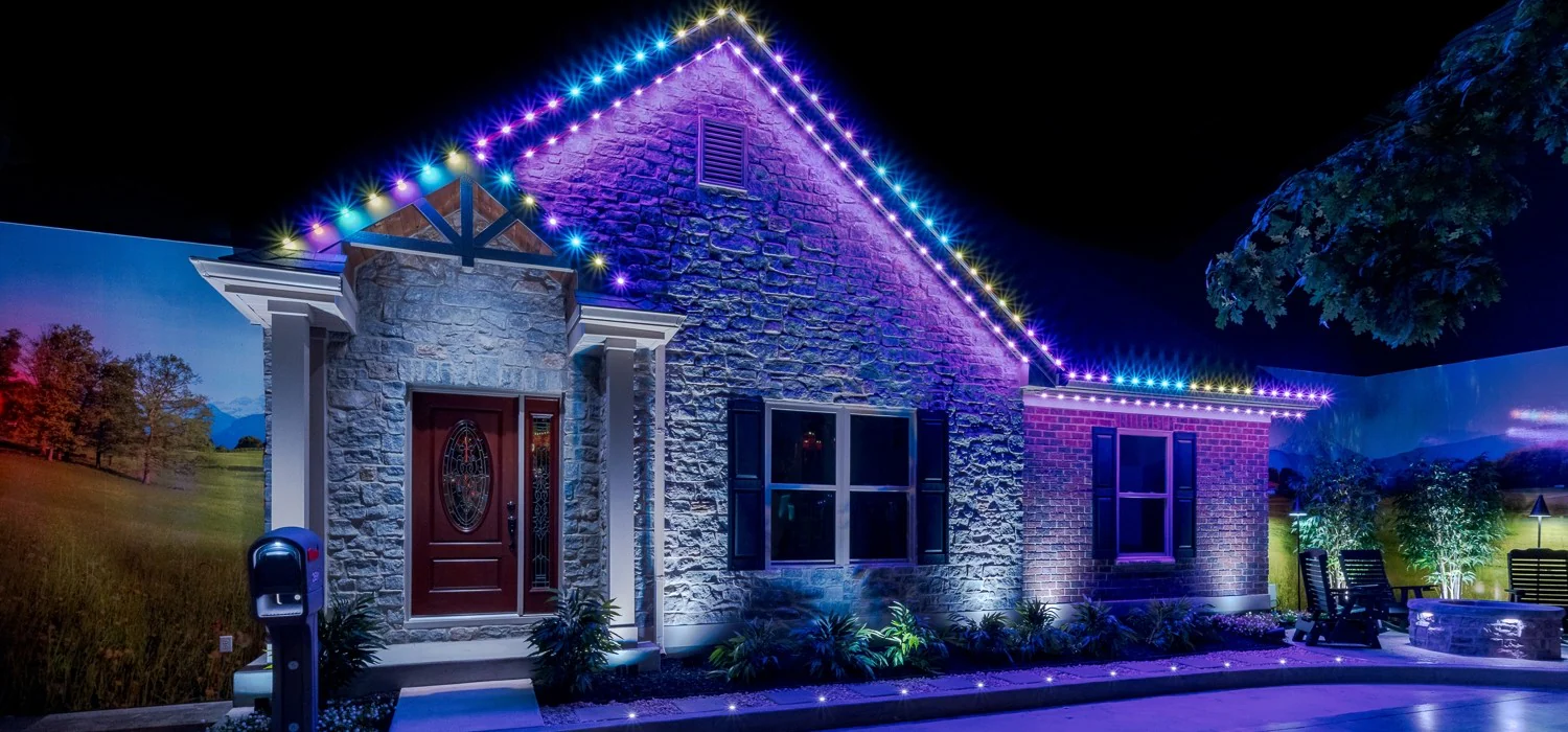 Purple and blue permanent exterior lighting accenting the roofline and front facade of a home at night.
