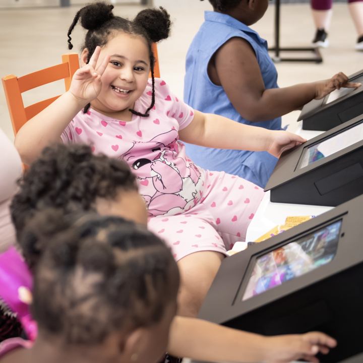 Family using the interactive touchscreen area at a Speed Queen Laundry location while completing the 