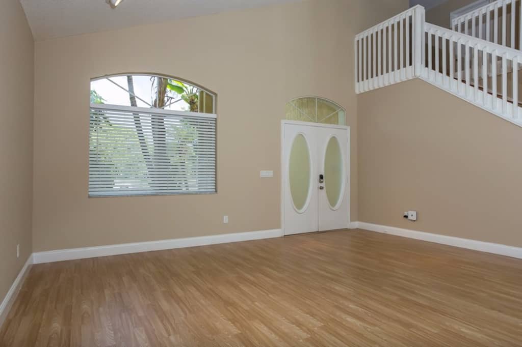 Spacious living room with wood flooring and high ceilings at Invitation Homes South Florida.