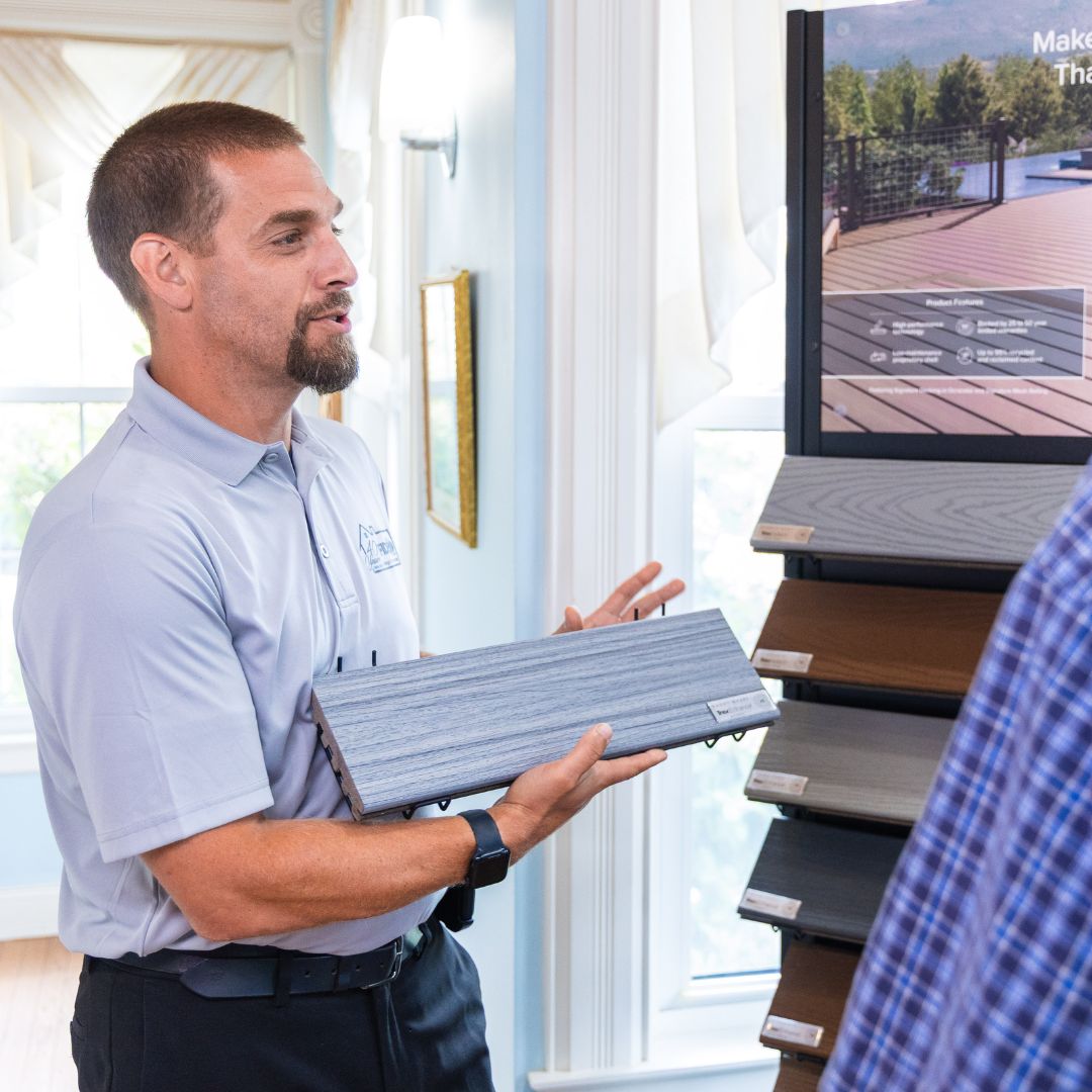 A Fiderio team member presents composite decking options to a customer inside the showroom.