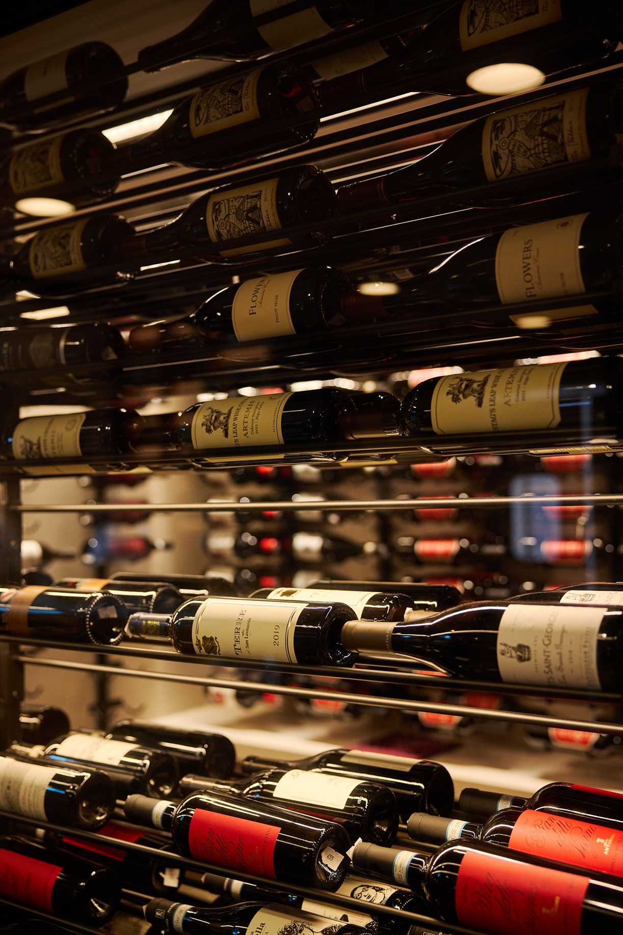 Extensive wine cellar display featuring various vintages of red and white wines, including labels from Toscana and Napa Valley.