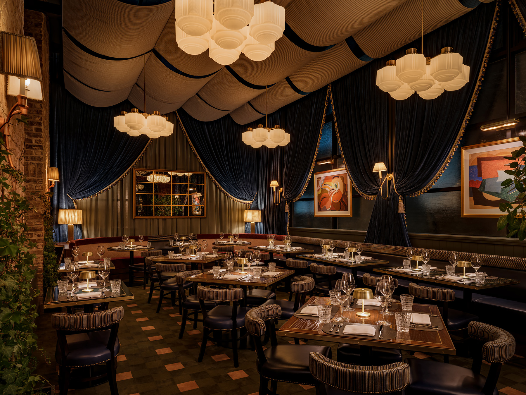 Upscale dining area with blue velvet drapes and warm pendant lighting at Carversteak NYC.