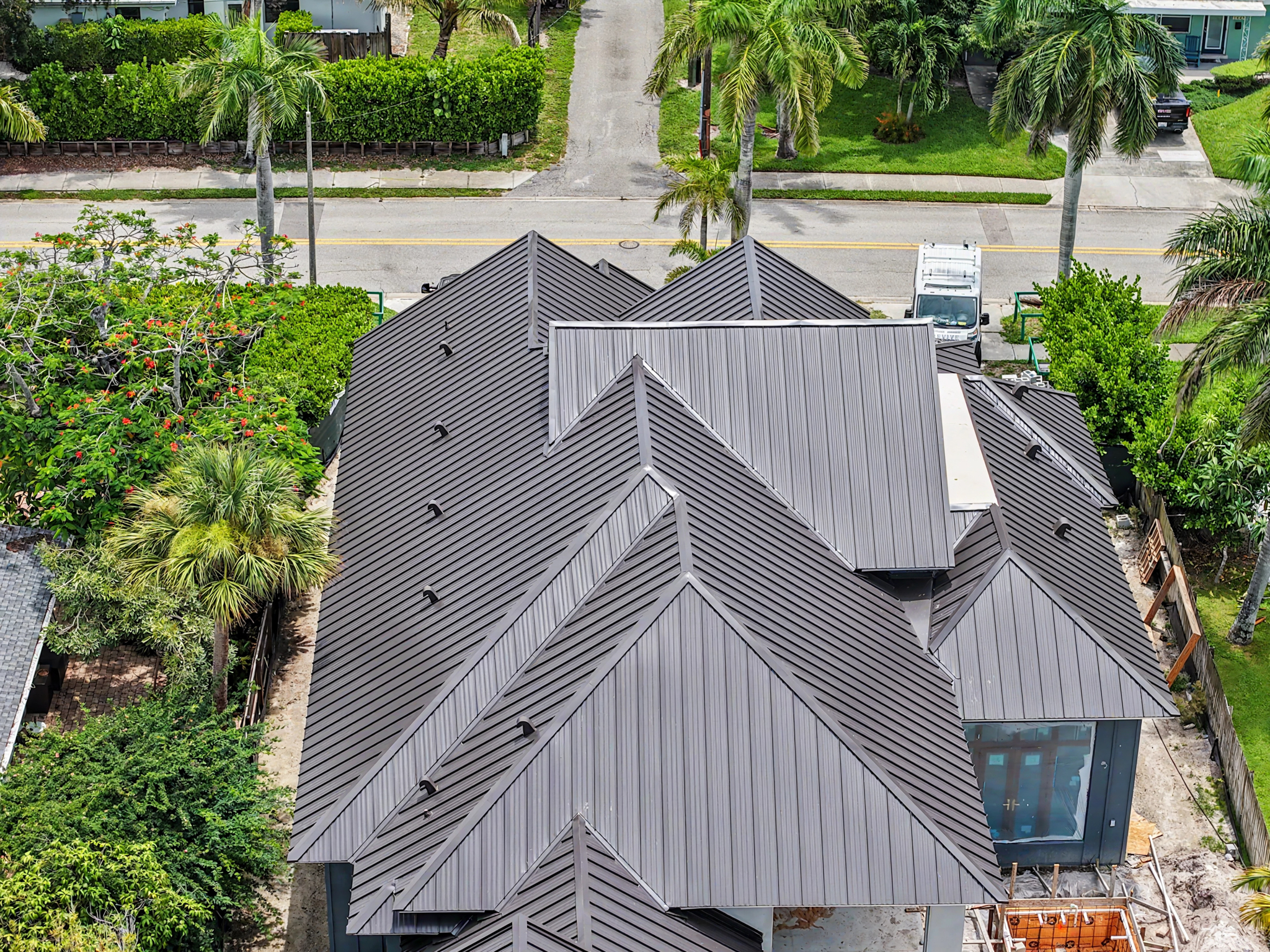 Aerial view of a residential property featuring a light gray standing seam metal roof with multiple  