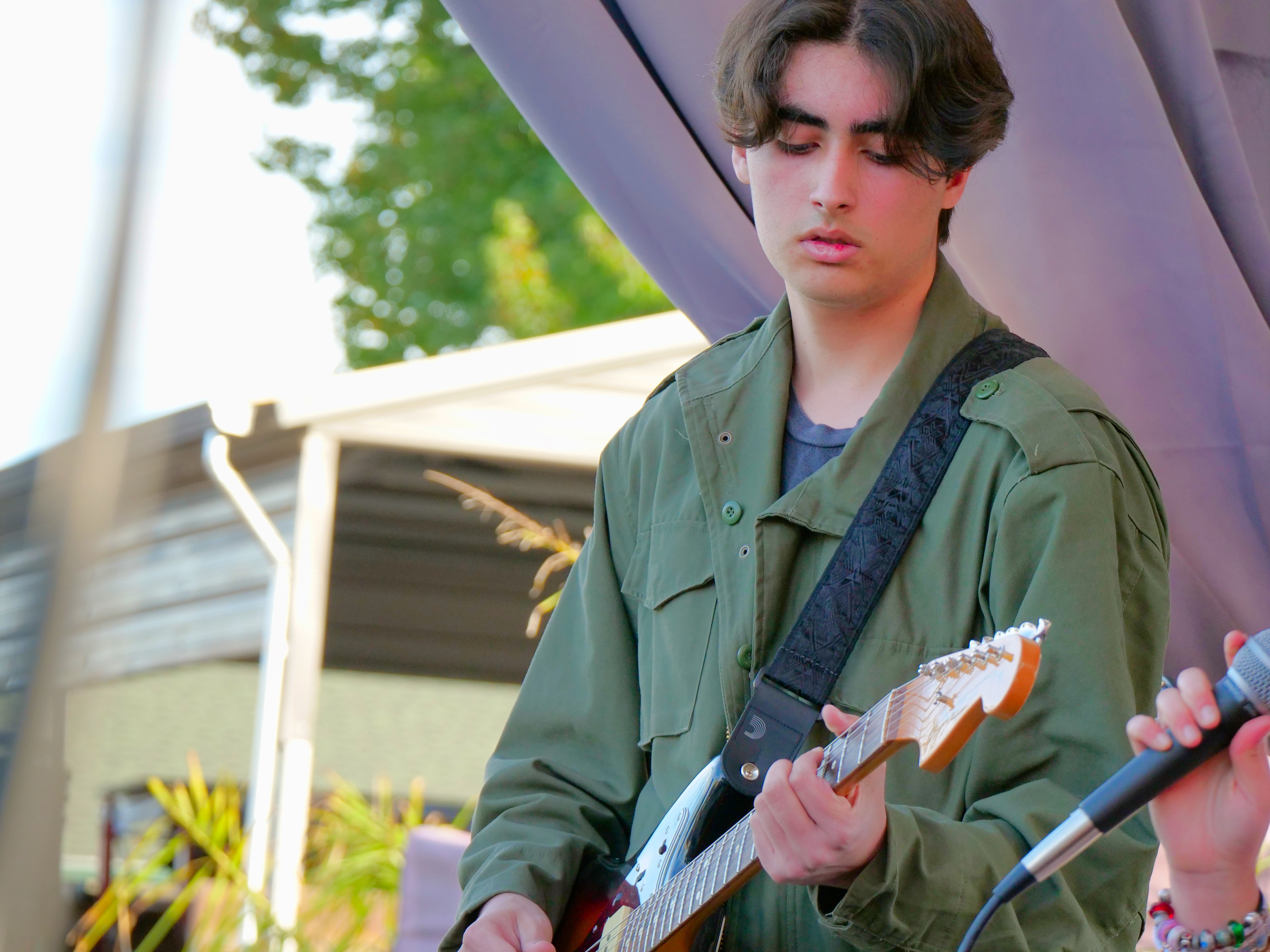 Student guitarist performing outdoors, highlighting hands-on music lessons and live performance experience.