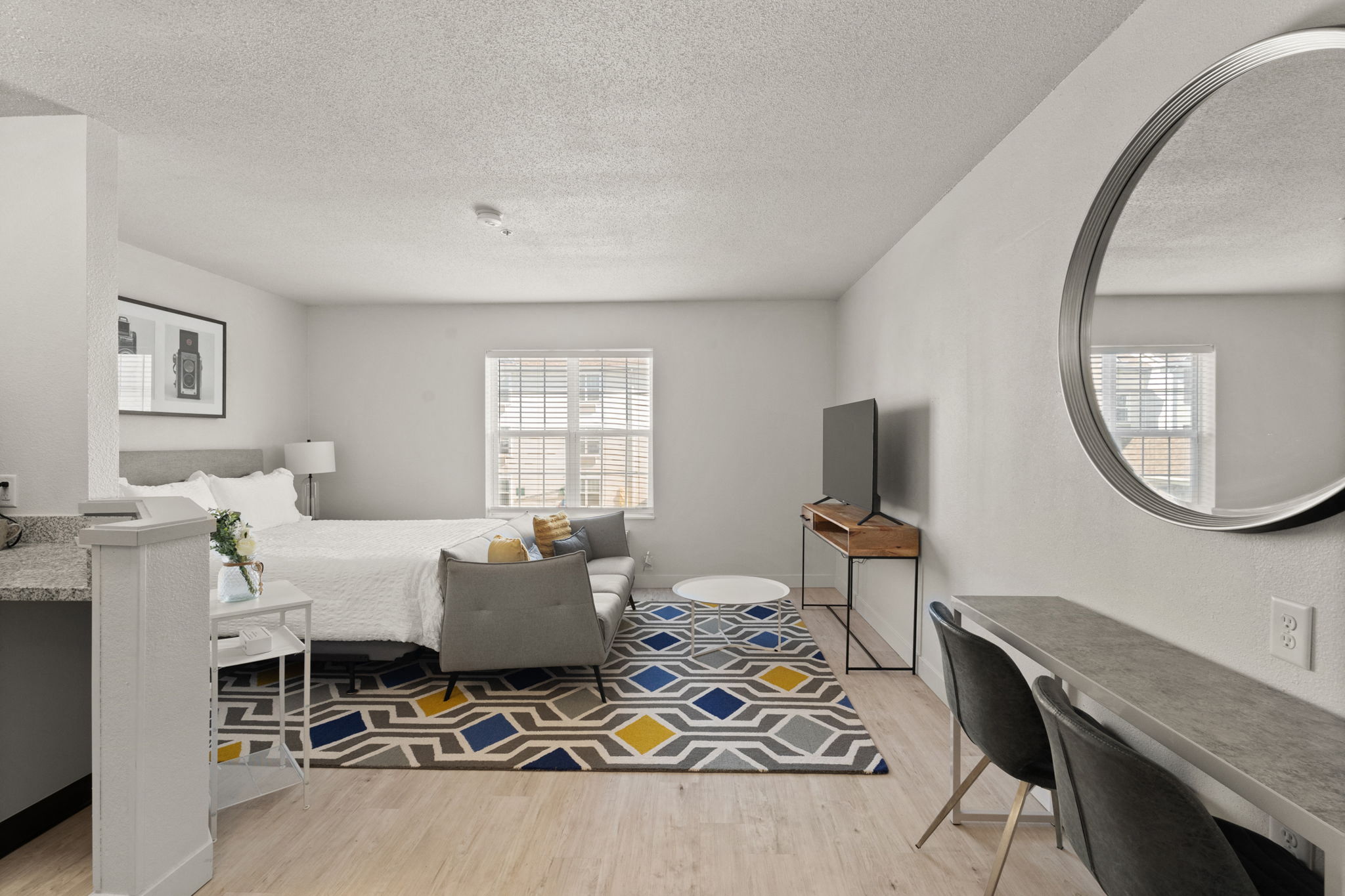 A bedroom with a bed and a desk and a living room at AVIA North Shore in Jeffersonville, IN