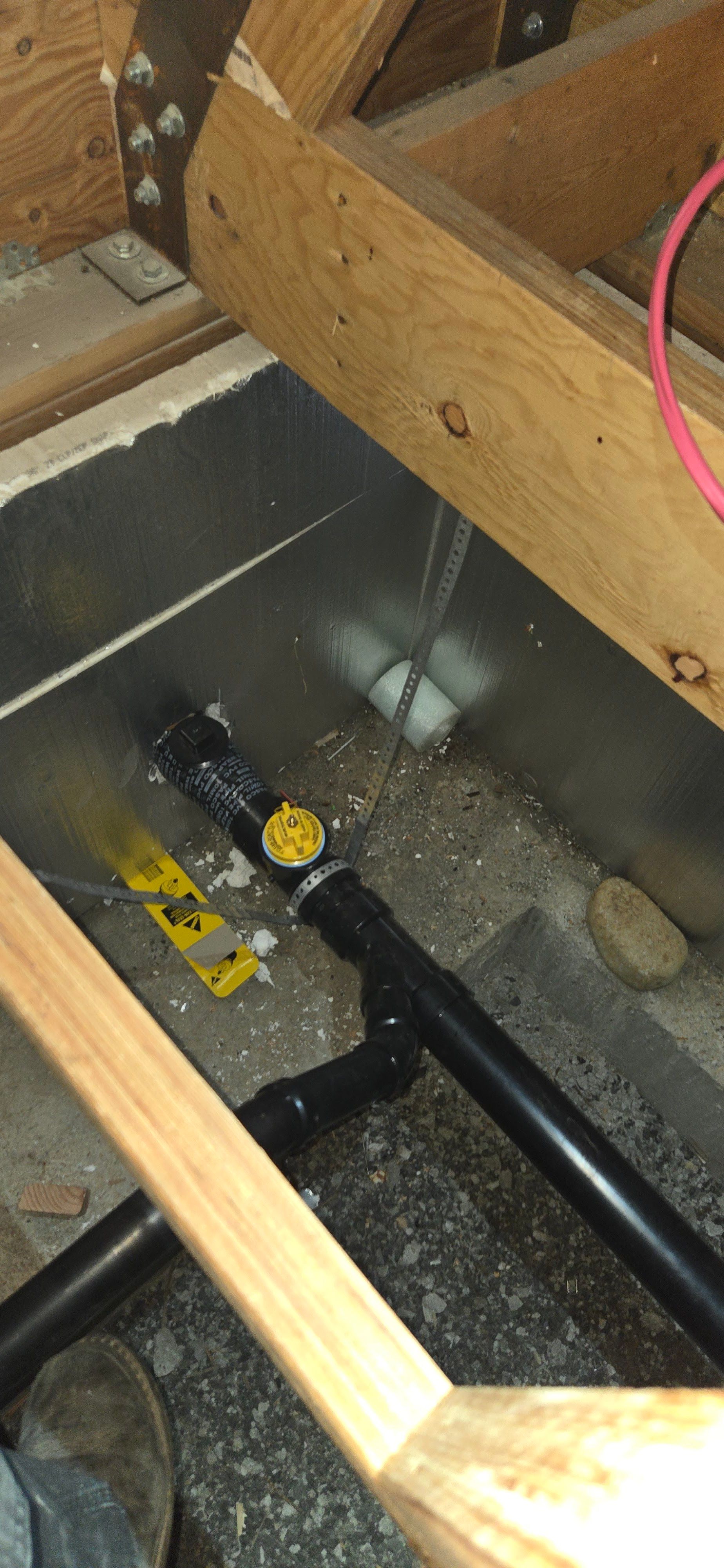 Plumbing installation inside a crawlspace showing black drain pipes connected with fittings and a cl 