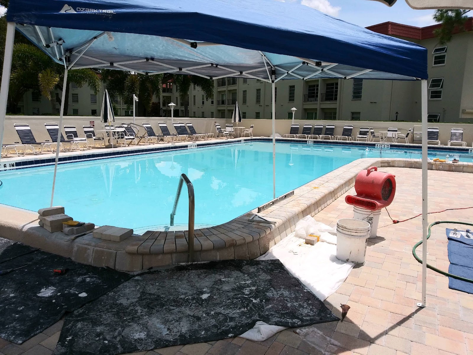 Commercial pool renovation project showing construction work underway around the pool deck and surrounding area.