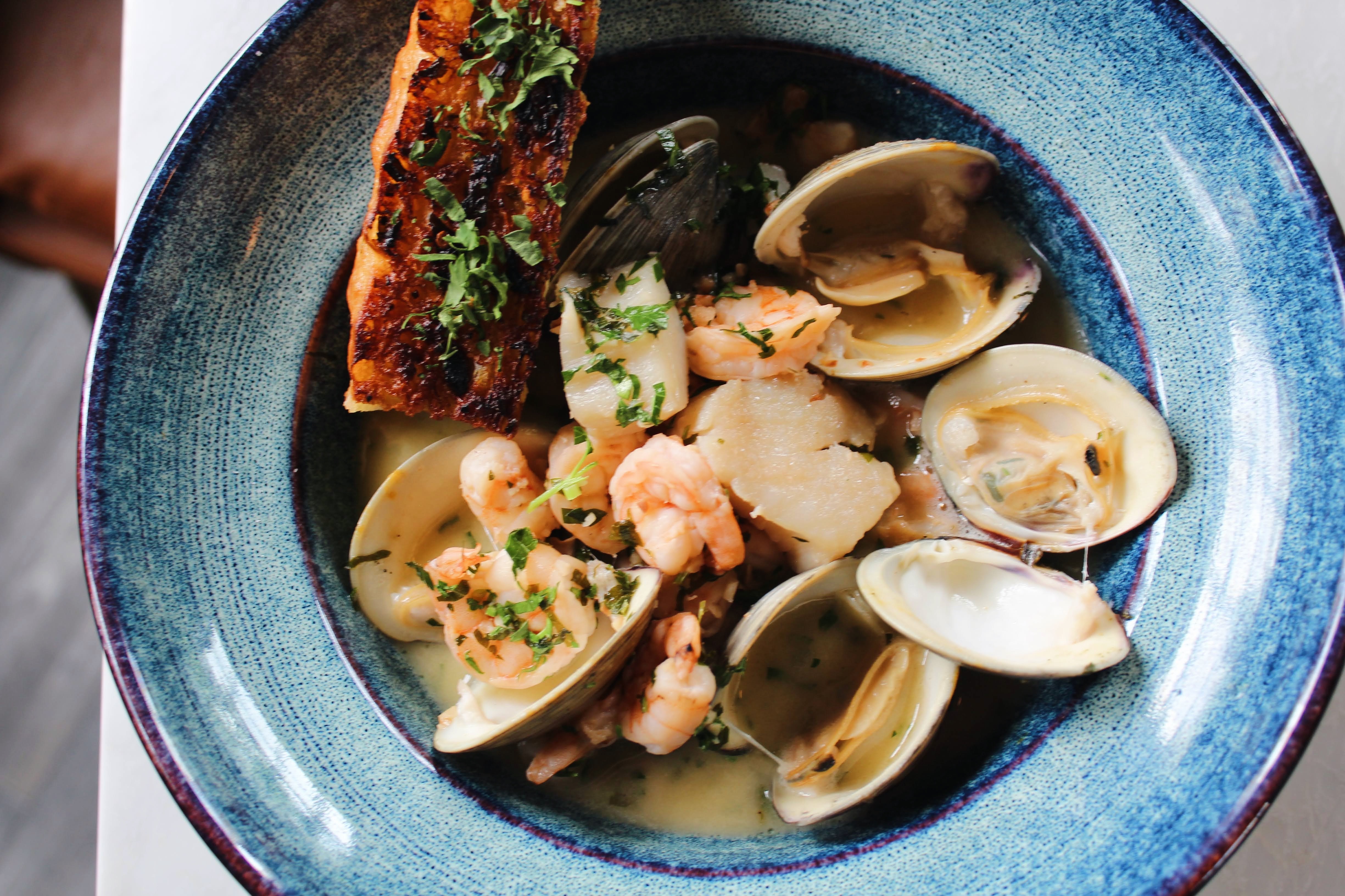 A second look at our Italian Seafood Scampi — briny clams, plump shrimp, and sweet scallops in a white wine, lemon, and garlic butter broth, with charred focaccia for dipping.