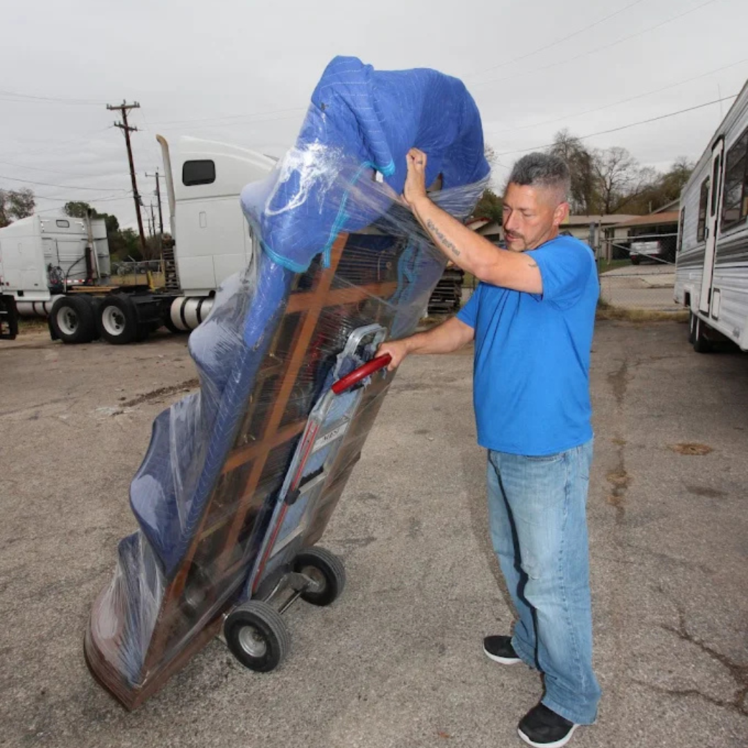 Mover transporting a padded furniture piece on a dolly during an Econo Move & Storage residential mo 