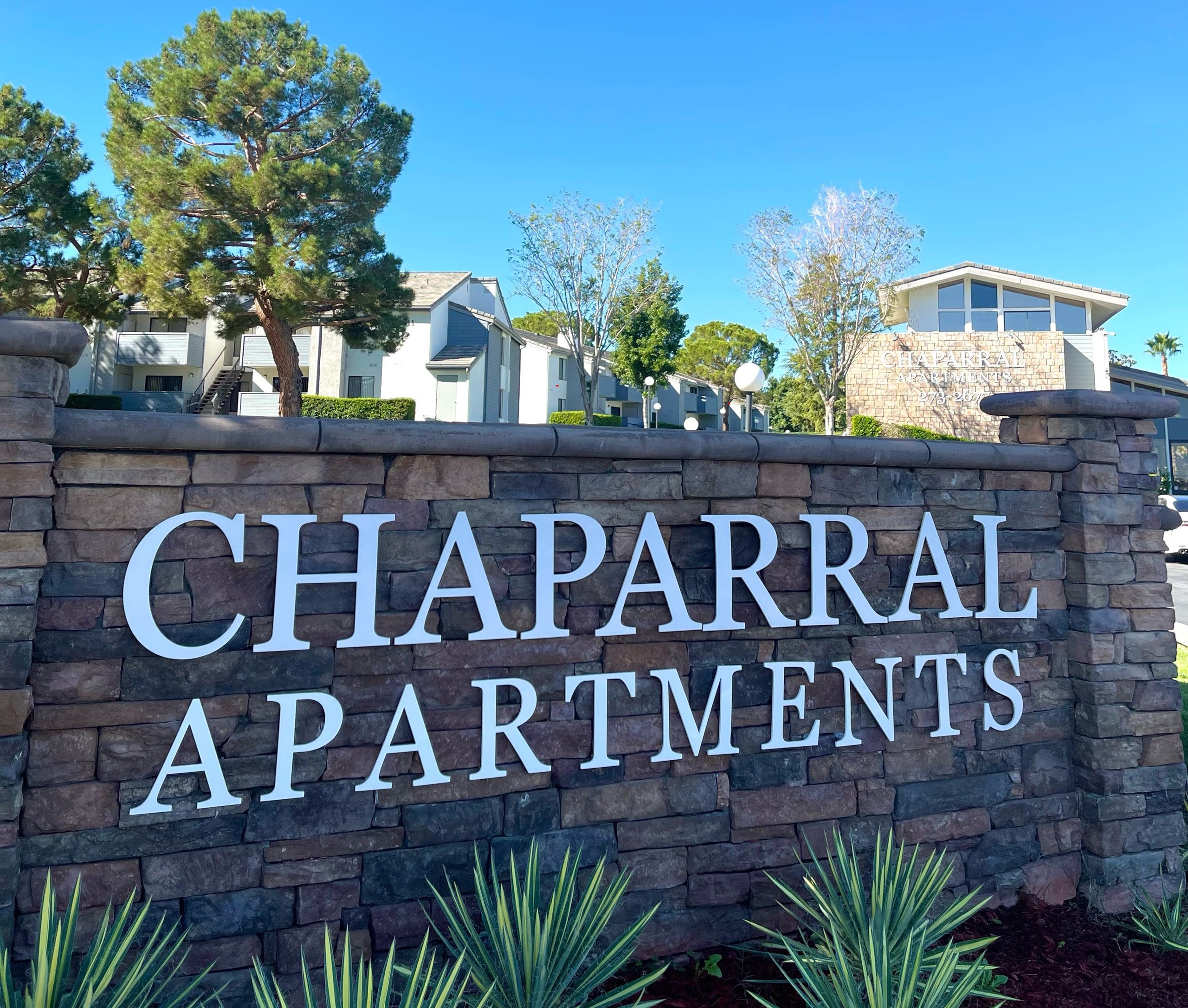 A sign that says Chaparral Apartments in front of some houses