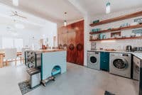 Bright laundry room featuring installed washer and dryer units, open shelving, storage cabinetry, and organized workspace, demonstrating professional appliance installation and efficient home utility design.