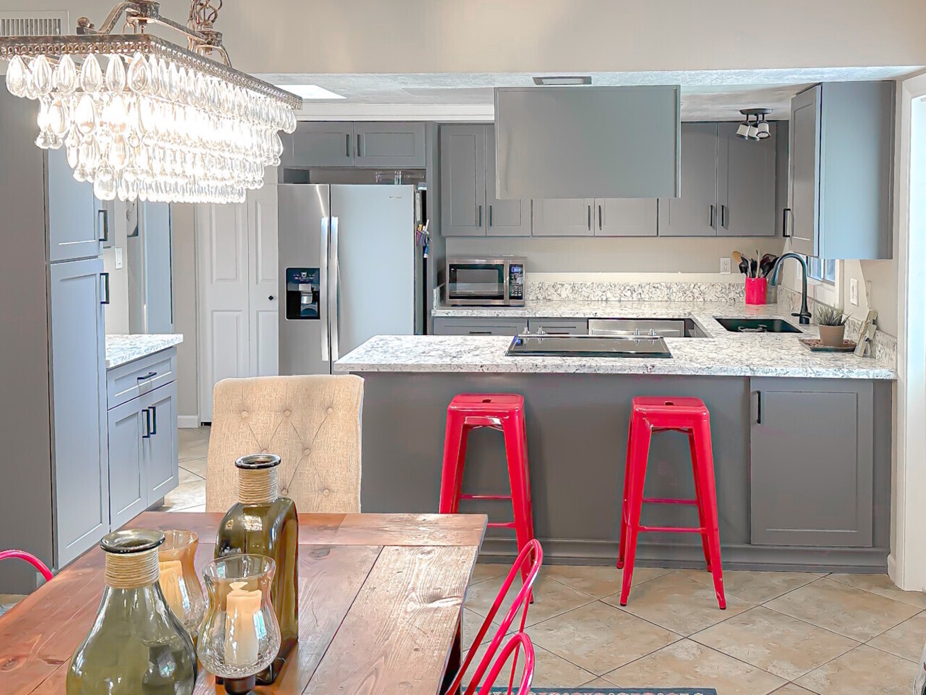 Remodeled kitchen featuring gray cabinetry, a peninsula with seating, light countertops, updated fix 