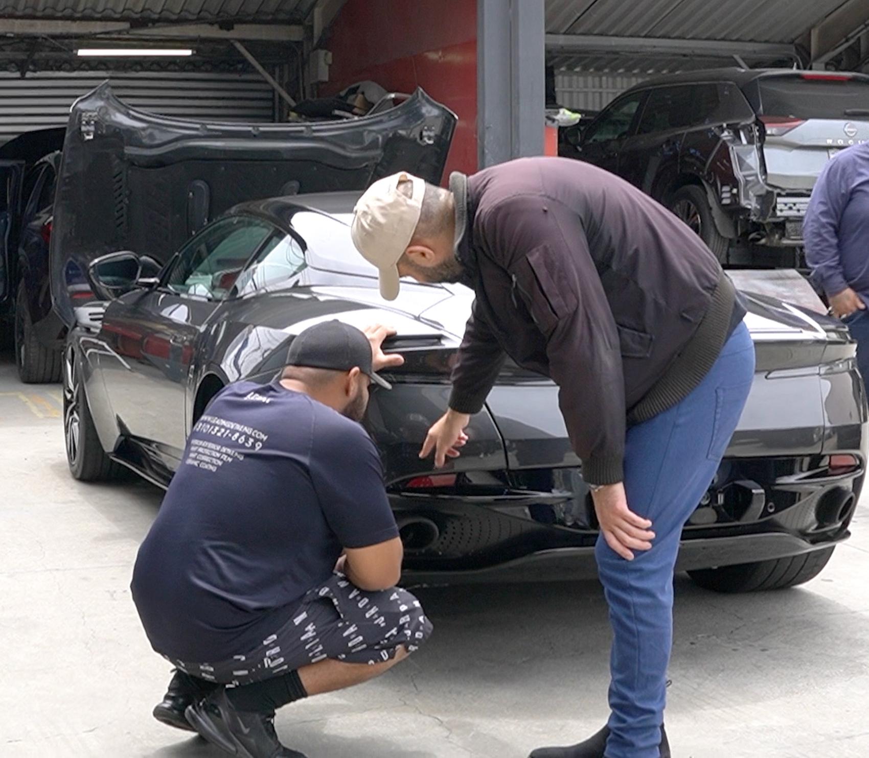 Detailing team inspecting Aston Martin at auto body shop parking lot after a successful collision repair