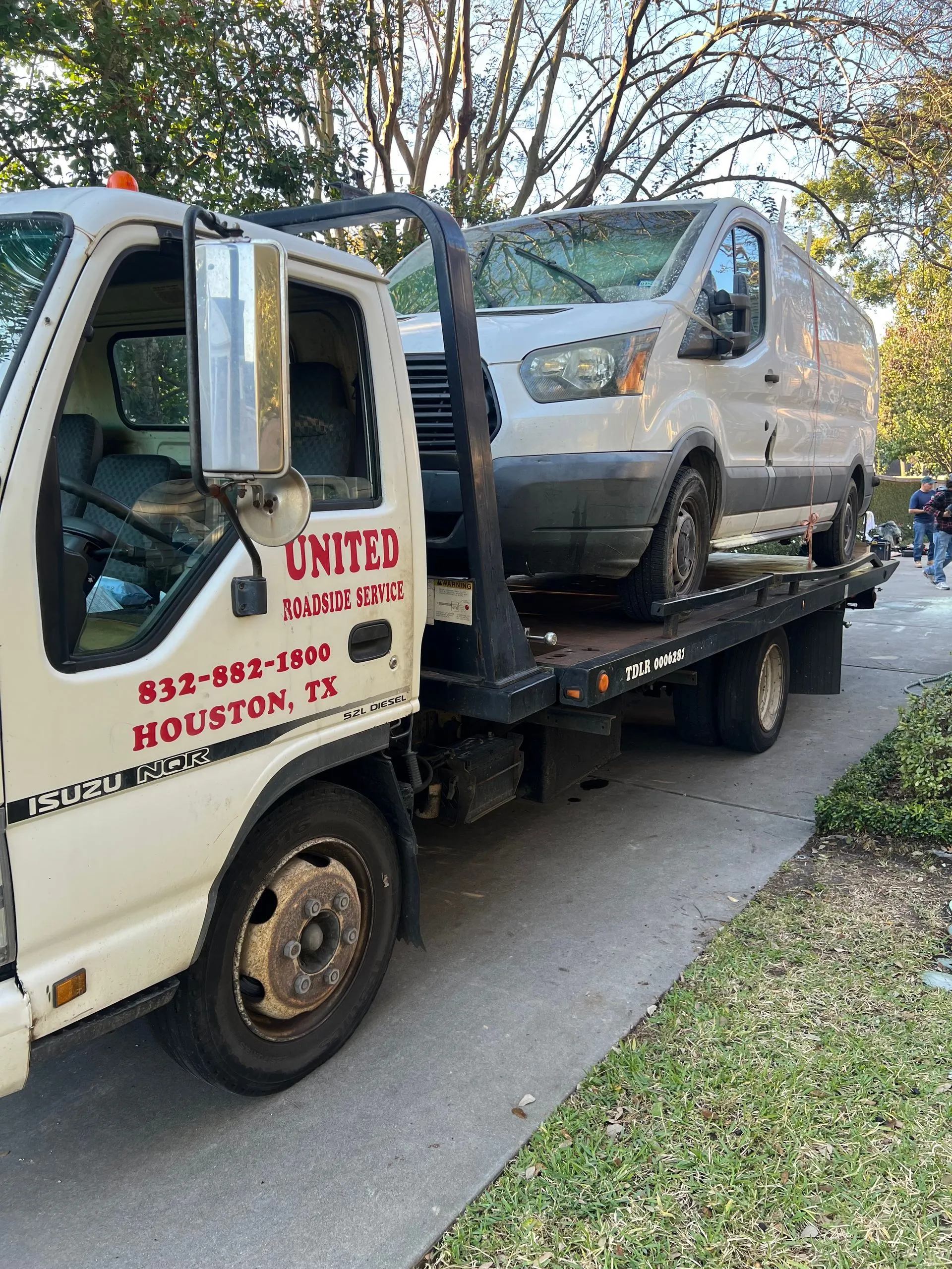 A white cargo van is securely loaded onto a United Roadside Service flatbed tow truck, demonstrating professional commercial vehicle towing, careful transportation, dependable roadside assistance, and reliable recovery services.