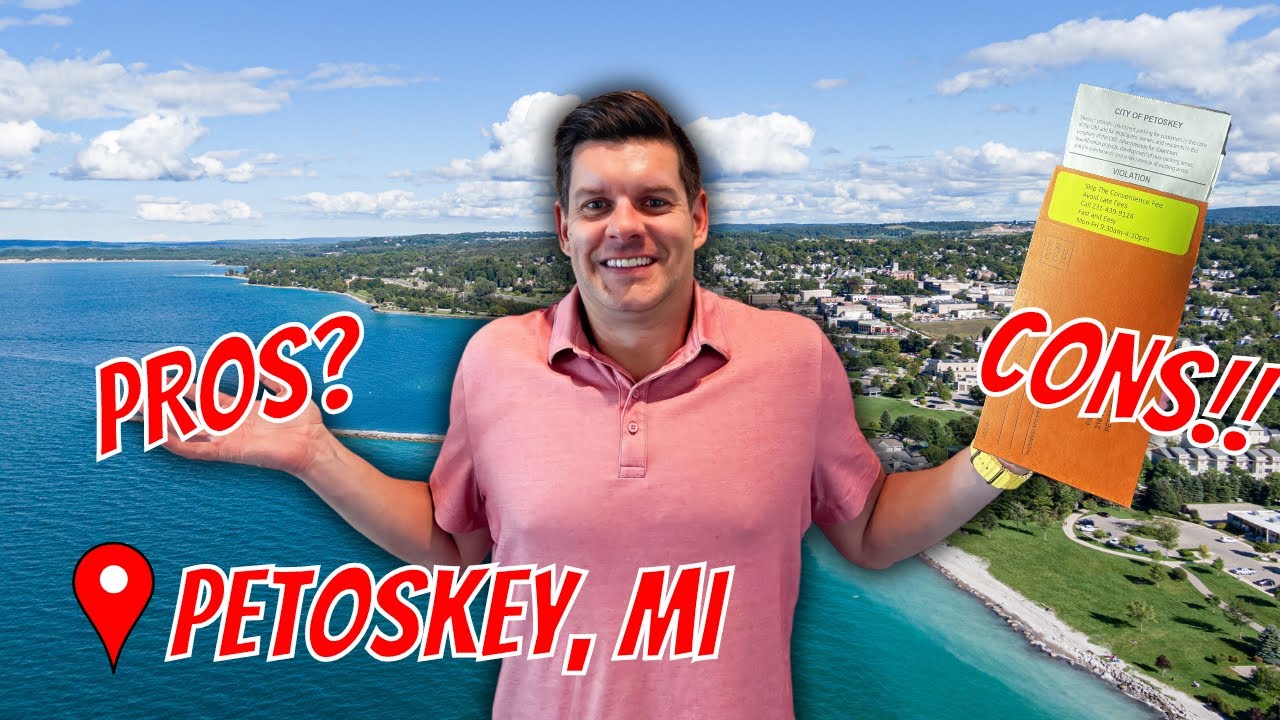 A man stands in front of a scenic view of Petoskey, Michigan, holding a document in an envelope and gesturing with his hands. Large red text overlays the image, with "PROS?" on the left and "CONS!!" on the right. A red location pin with the text "PETOSKEY, MI" is visible in the lower left corner. The man is wearing a pink polo shirt, and the background shows a blue lake, a tree-lined town, and a cloudy sky.