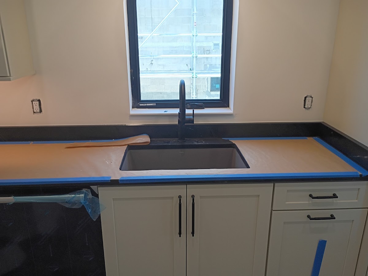 Kitchen sink area with new faucet and countertop protection in place during plumbing installation or renovation work.