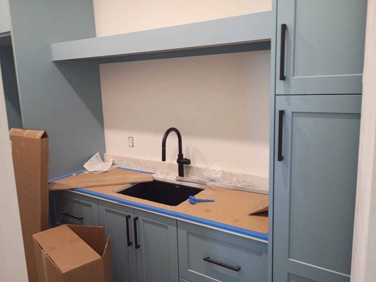 Kitchen sink and faucet installation with surrounding cabinetry and countertops prepared during a plumbing or remodeling project.