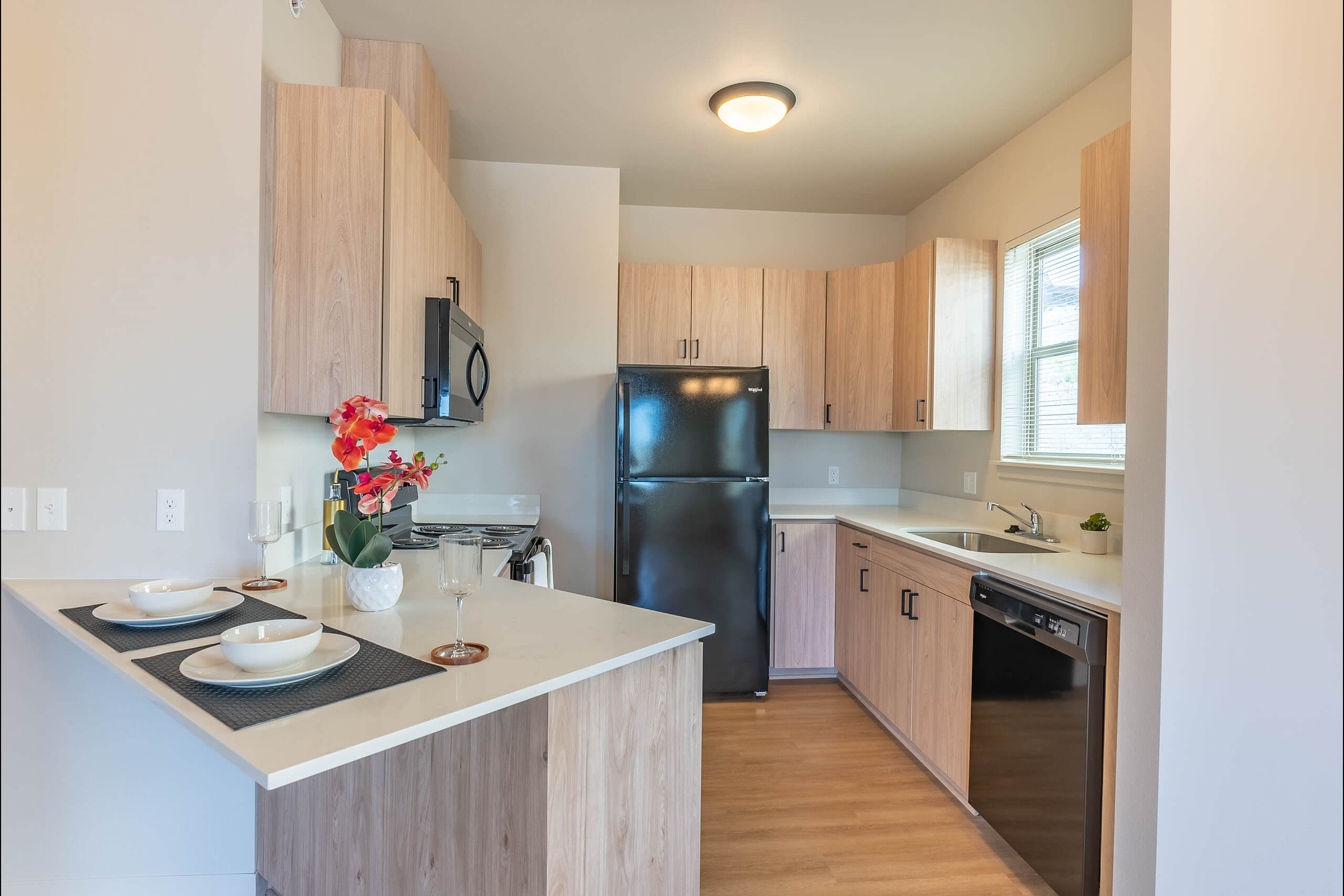 A kitchen with a black refrigerator and wooden cabinets.