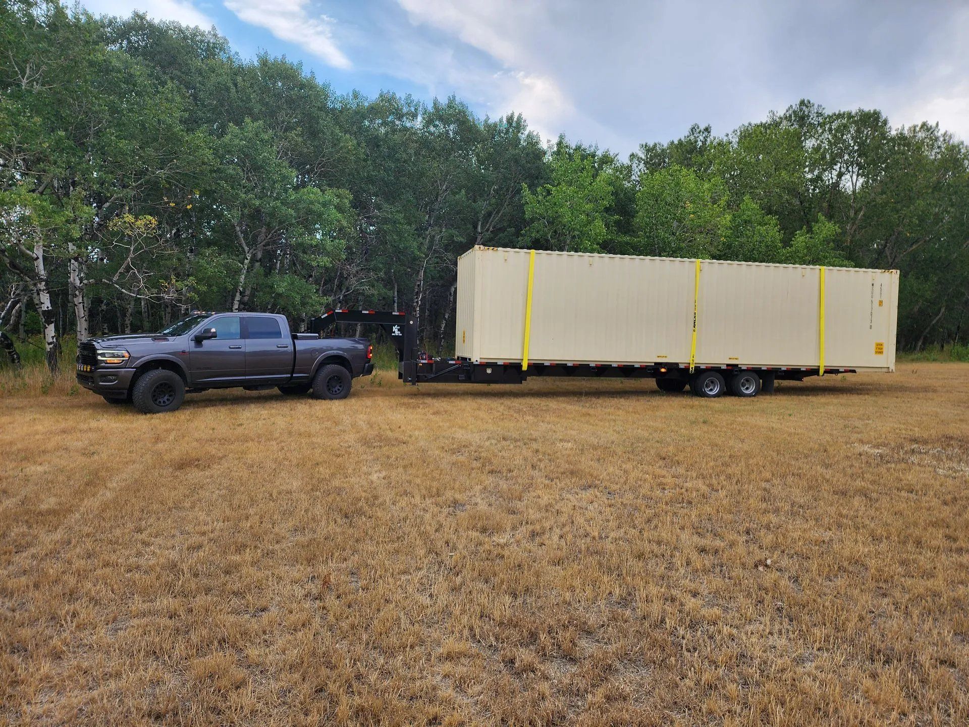 Heavy-duty truck towing long portable storage container across open field, highlighting mobile storage delivery service and easy transportation for residential, construction, or commercial storage needs in various environments.