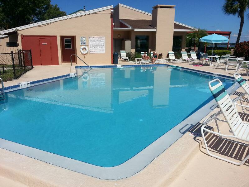 A backyard inground pool with an integrated raised spa and custom coping, set on a stone paver deck alongside a home exterior.