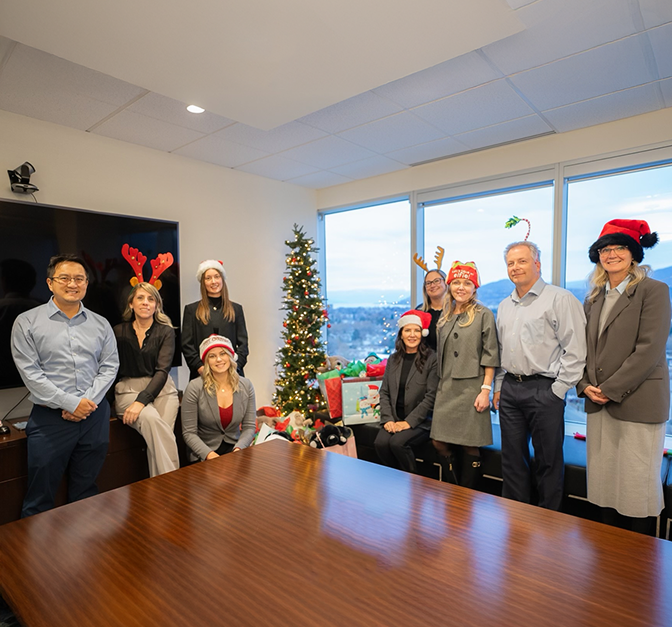The Hymers Private Wealth Team posing beside a Christmas tree and gifts.