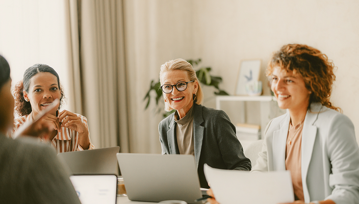 Professionals in the middle of a meeting with their laptops open.