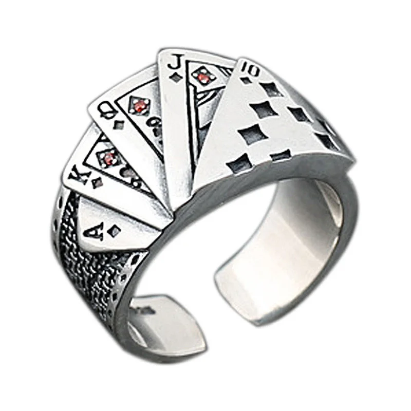 A close-up, studio shot of a silver ring designed to resemble a fan of playing cards, with a white background. The cards shown are an Ace, King, Queen, Jack, and 10, all of diamonds, with small red stones accenting the pips on some cards. The ring band has a textured, possibly woven or cross-hatched pattern on the sides. It is an open-cuff ring, allowing for adjustable sizing.