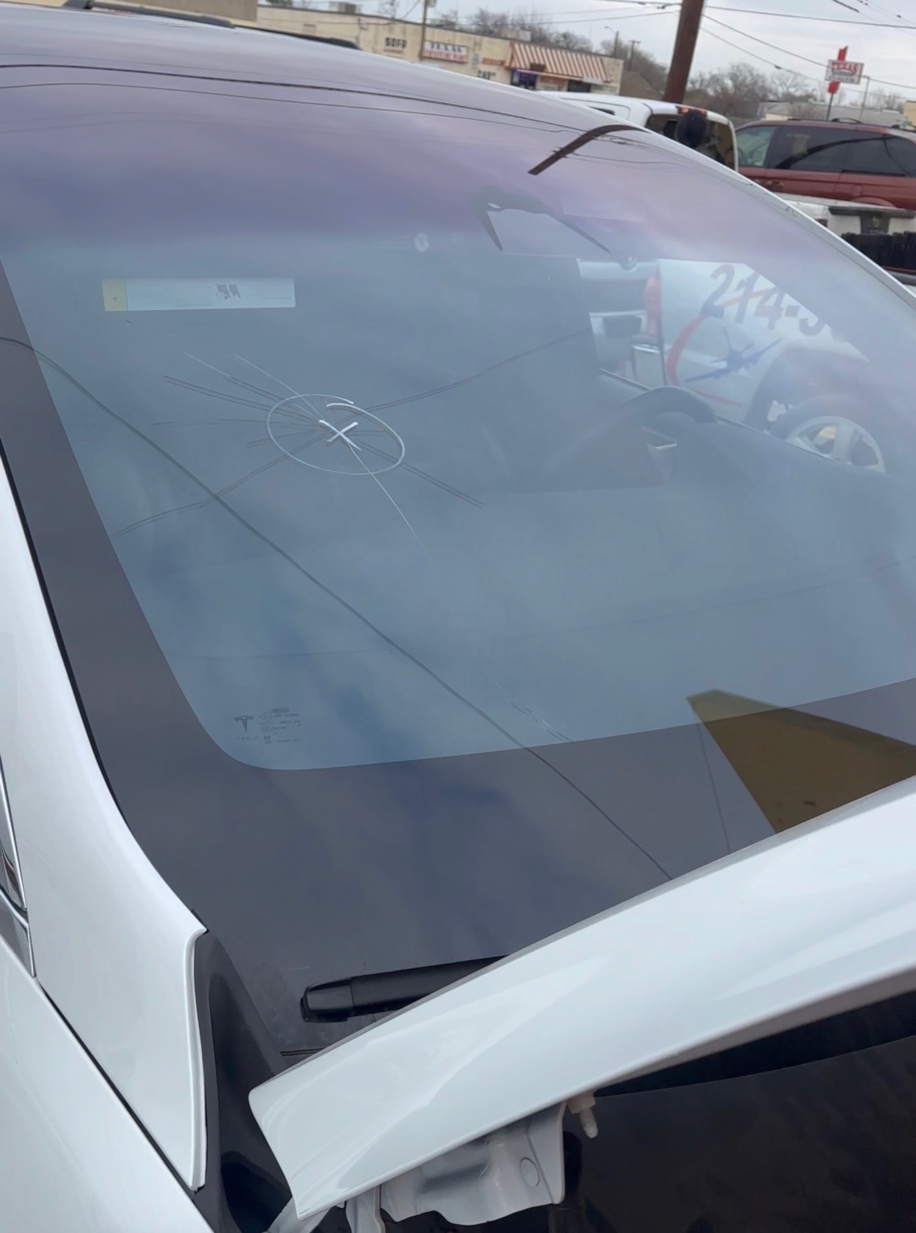 A white Tesla is shown outside Space Auto Glass with the front glass area being prepared during windshield service. The photo highlights auto glass replacement capabilities for electric vehicles.