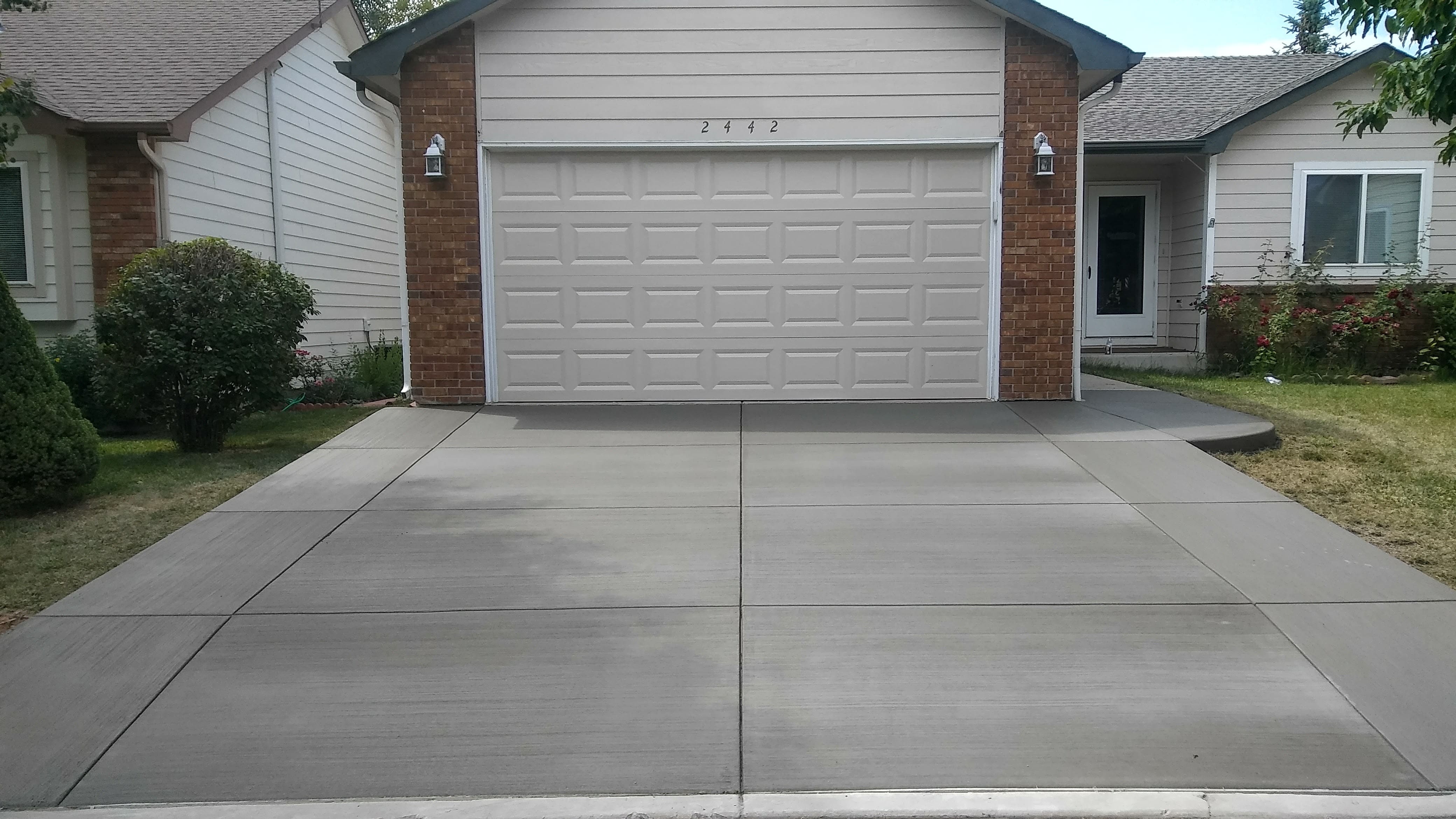 New residential concrete driveway with a clean, uniform finish, defined control joints, and a wide layout providing convenient access to the garage.