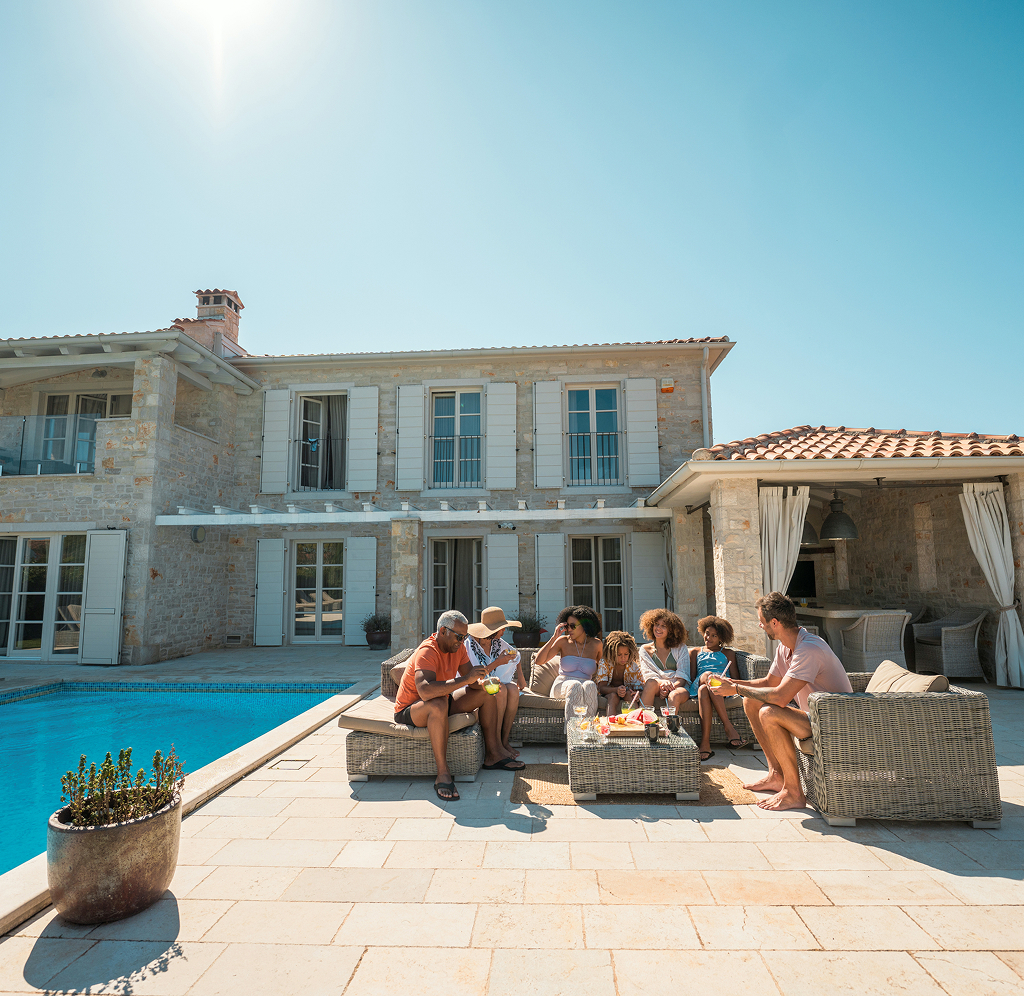A family enjoying poolside refreshments on a sunny day in the backyard of their home.