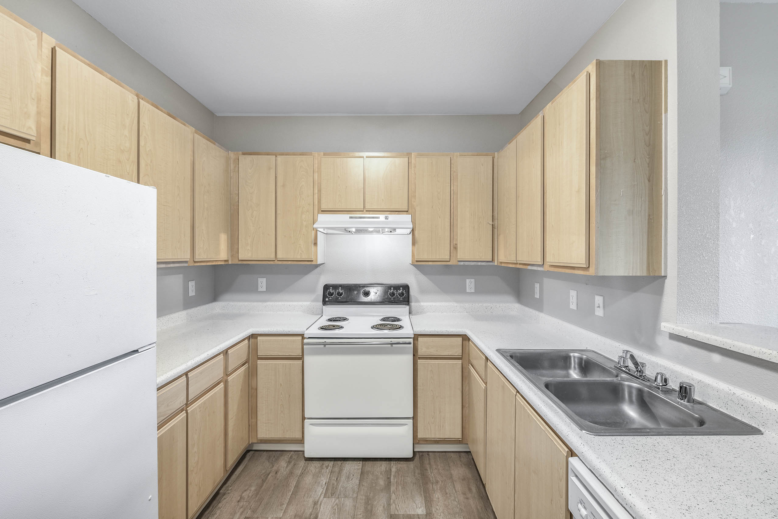 Galley kitchen with electric range and light wood cabinetry