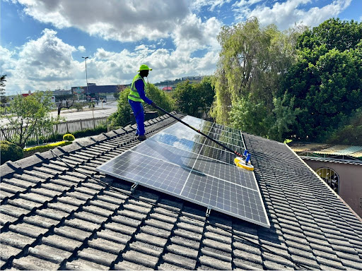 Residential rooftop solar panel cleaning on a tile roof, showing a professional using dedicated equipment to clean a home solar array.