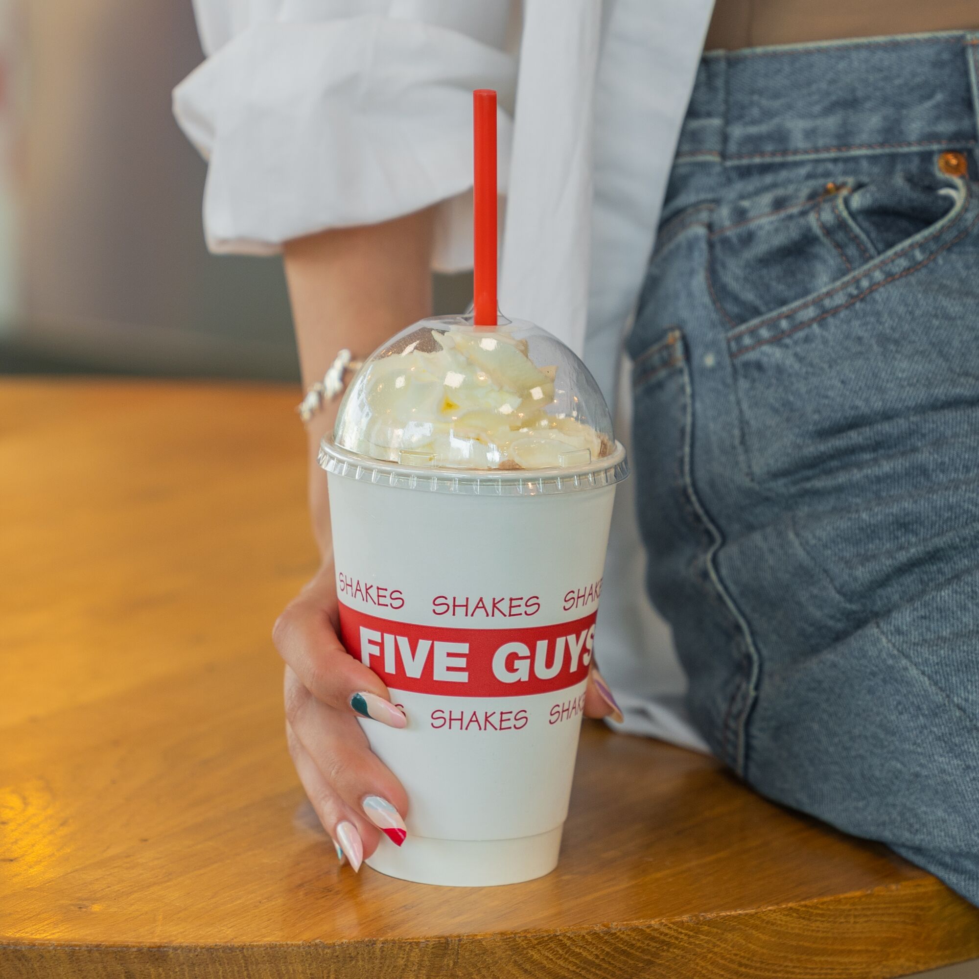 A close-up photograph of a woman holding a Five Guys milkshake. Five Guys Ottawa (613)562-8119